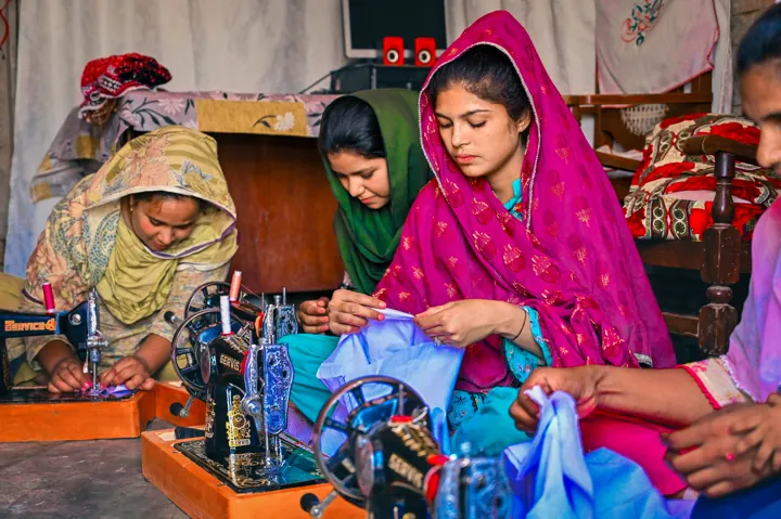 Women learning and working together at sewing machines