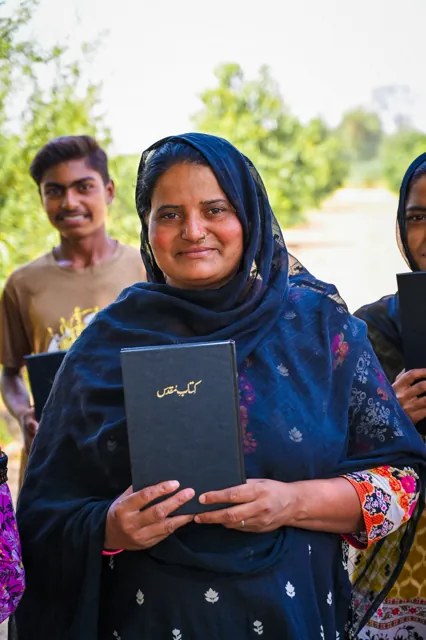 A woman holding a Bible at an outdoor distribution
